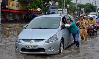 Một CSGT dầm mình trong nước nỗ lực đẩy chiếc xe ô tô bị chết máy.