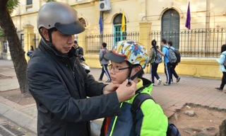 Trẻ em từ 6 tuổi trở lên khi ngồi trên xe gắn máy bắt buộc đội mũ bảo hiểm cài quai đúng quy cách. Ảnh: Thanh Hà.