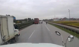 Các thanh niên đi xe máy không đội mũ đánh võng trước mặt container