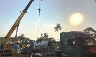 Máy bay chiến đấu Mig đã tháo rời cánh dễ dàng bị siêu cần cẩu nhấc bổng đưa lên xe tải siêu trường siêu trọng chờ di chuyển đi trong đêm.