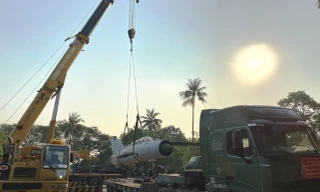 Máy bay chiến đấu Mig đã tháo rời cánh dễ dàng bị siêu cần cẩu nhấc bổng đưa lên xe tải siêu trường siêu trọng chờ di chuyển đi trong đêm.