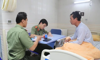 Cán bộ A08 làm thủ tục cấp hộ chiếu cho bệnh nhân tại giường bệnh.