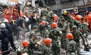 Các nhân viên cứu hộ dùng tay bới đống đổ nát cứu người mắc kẹt trong vụ sập nhà ở Ôn Châu, Trung Quốc.