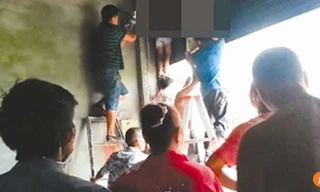 Dân làng phải mất 1 tiếng đồng hồ để gỡ hai em ra khỏi chiếc cửa cuốn