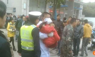 Các nhân viên y tế đưa một em nhỏ bị thương ở đầu lên xe cấp cứu.