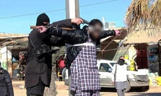 Phiến quân IS chĩa súng vào đầu nạn nhân bị trói trên thập giá giữa phố ở Raqqa.