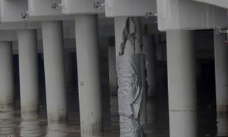 Trụ cầu được cuốn tấm bạt che chắn nhưng vẫn để lộ vết vứt vỡ, có thể nhìn thấy cả những thanh sắt bên trong. Ảnh: Tùng Chi.