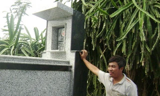 Anh Châu Văn Đông đứng bên mộ vợ, chị Đinh Thị Lan đã chết do bị điện giật ở vườn thanh long Ảnh: Châu Thành