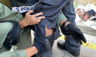 Một cảnh sát Hong Kong bị tên bắn vào chân. Ảnh: AP.