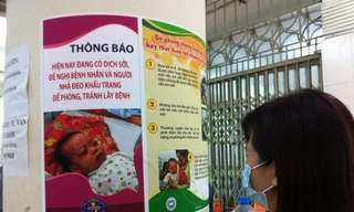  Người dân đọc khuyến cáo về phòng bệnh sởi. Ảnh: Thùy Giang/Vietnam+)