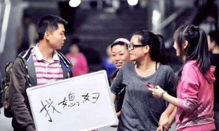 Một chàng trai mang theo tấm biển “tìm người lấy làm vợ” 