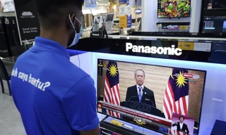 Nhân viên một cửa hàng điện tử ở Kuala Lumpur xem Thủ tướng Muhyiddin phát biểu trên truyền hình ngày 12/1. (Ảnh: AP)