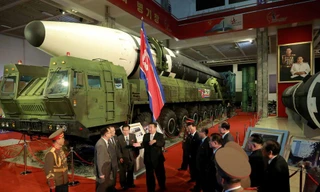 Chủ tịch Triều Tiên Kim Jong Un phát biểu với một số quan chức khi đứng cạnh các vũ khí được đưa ra triển lãm hôm 12/10. (Ảnh: KCNA)