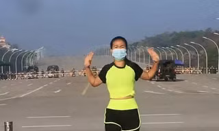 Người phụ nữ đang tập thể dục trước dàn xe quân sự