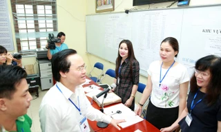 Bộ trưởng Phùng Xuân Nhạ trò chuyện với cán bộ, giáo viên làm công tác coi thi, phục vụ thi tại điểm thi THPT Yên Viên - Gia Lâm, Hà Nội. Ảnh: Như Ý. 