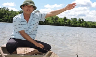 Ngư phủ Cảnh kiểm tra mồi câu trên sông.