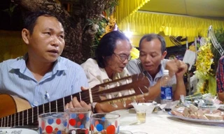 Tác giả Bùi Long ôm đàn trong đám tang thi sĩ Trần Vàng Sao. Ảnh: Trần Tuấn.