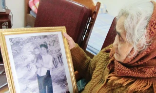 Cụ Khương Thị Chu- mẹ liệt sĩ Lê Đình Chinh- với bức ảnh kỷ niệm Chinh hồi nhỏ. Ảnh: Hoàng Lam