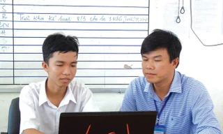 Em Trần Lê Duy (bên trái) và thầy Võ Việt Dũng kiểm tra một số phần mềm đã lập trình. Ảnh: Kim Hà.
