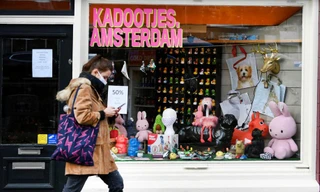Một người phụ nữ đeo khẩu trang đi bộ ở Amsterdam (Hà Lan). Ảnh: Reuters