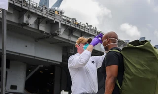 Thuỷ thủ tàu sân bay USS Roosevelt được kiểm tra thân nhiệt trước khi trở lại tàu. Ảnh: Reuters
