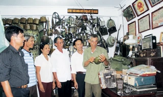 Ông Bùi Đình Thu (mặc áo lính) giới thiệu các kỷ vật chiến tranh cho khách tham quan.