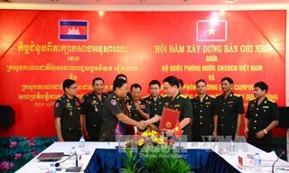 Đại tá Hàn Mạnh Thắng, Vụ trưởng Vụ Pháp chế (Bộ Quốc phòng Việt Nam, bên phải) và Đại tướng Mom Sophat, Cục trưởng Cục pháp chế (Bộ Quốc phòng Vương quốc Campuchia) ký biên bản hội đàm.
