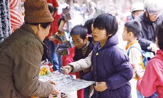 Học sinh tiểu học ở Hà Nội đang mua miếng dán độc hại có xuất xứ Trung Quốc trước cổng trường. Ảnh: Như Ý.