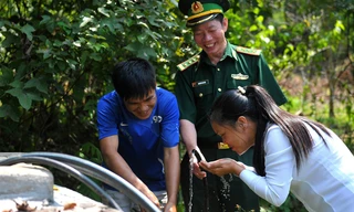 Niềm vui của người lính biên phòng Pò Mã và người dân thôn Nà Lẹng bên bể nước sạch trong thôn. Ảnh: Xuân Tùng.