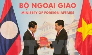 Phó Thủ tướng, Bộ trưởng Ngoại giao Phạm Bình Minh và Bộ trưởng Ngoại giao Lào Saleumxay Kommasith trao đổi tượng trưng hai ấn phẩm văn kiên pháp lý biên giới Việt Nam-Lào. (Ảnh: Nguyễn Khang/TTXVN)