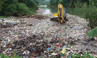 Hình ảnh máy xúc gạt rác xuống suối khiến người dân bức xúc. Ảnh: Chương Nhàn.