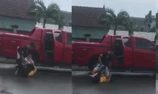 Người phụ nữ bị đánh đập dã man cạnh chiếc ô tô bán tải màu đỏ. Ảnh Cắt từ clip
