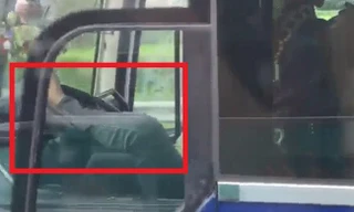 Tài xế xe khách dùng chân điều khiển xe đã bị người đi đường ghi lại clip. Ảnh cắt từ clip.