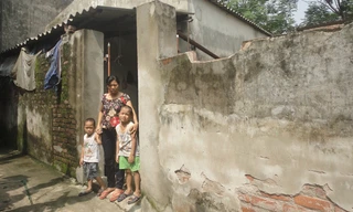 Chị Nhâm và hai con trước căn nhà xuống cấp. Ảnh: K.N