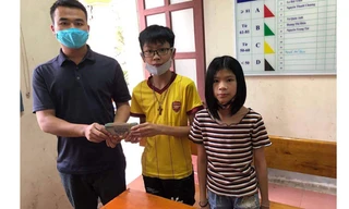 Em Hải (áo vàng ở giữa) trao lại số tiền nhặt được cho đại diện Công an phường Nam Hà.