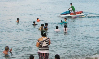 Một chiếc mô tô nước chạy sát phụ nữ và trẻ em đang tắm biển, ảnh chụp chiều 28-5.