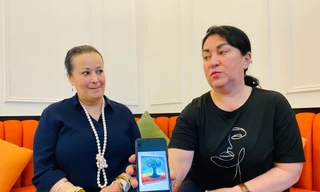 Họa sĩ Badia Maidat (phải) giới thiệu bức tranh “Sự kiên cường” sau khi em gái Siham Maidat kể về mẹ. Ảnh: Thái An.