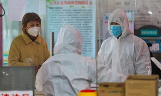 Nhân viên y tế tại một trạm y tế nói chuyện với một phụ nữ nghi nhiễm coronavirus ở Vũ Hán ngày 27/1. Ảnh: AP.