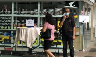 Nhân viên bảo vệ trung tâm thương mại Excelsior đeo khẩu trang, găng tay kiểm tra thân nhiệt mọi khách ra vào và hướng dẫn họ rửa tay bằng dung dịch sát khuẩn, đăng ký thông tin tại quầy trước cổng vào. Ảnh: Thái An.