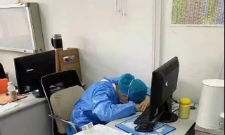 Bác sĩ chống dịch coronavirus mới ngủ gục tại bàn làm việc vì làm việc không nghỉ trong hàng chục giờ. Họ mặc nguyên đồ bảo hộ, đeo bỉm, thậm chí có người cạo trọc đầu... để tiết kiệm thời gian mặc đồ. Ảnh: CCTV News.