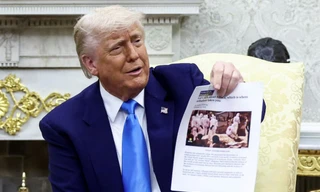 Tổng thống Mỹ Donald Trump giơ bài viết có hình ảnh vụ chôn tập thể ở Congo trong cuộc gặp Tổng thống Nam Phi. (Ảnh: Reuters)