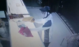 Tên cướp giơ vật gống khẩu súng được giấu trong chiếc túi màu vàng. Ảnh cắt từ video.