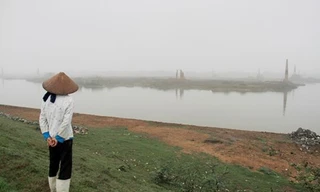 Một phụ nữ đứng trên đoạn đê mới được kè đá do bị sạt lở trên địa bàn xã Quế Tân (Quế Võ, Bắc Ninh). Ảnh: Trường Phong