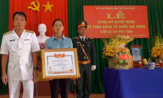 Bà Vân thay mặt gia đình đón nhận Bằng Tổ quốc ghi công cho con trai là liệt sĩ Lê Văn Tính ảnh: GĐCC