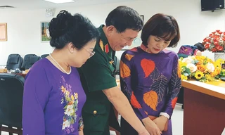 Anh hùng Phạm Tuân trao đổi với bà Nguyễn Minh Thủy (trái) về huy hiệu có chân dung Chủ tịch Hồ Chí Minh do cố hoạ sĩ Bùi Trang Chước vẽ Ảnh: KIẾN NGHĨA 