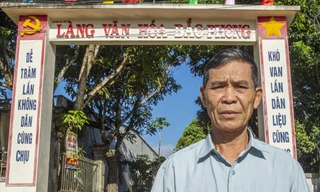 Ông Xa Văn Khoa, Bí thư chi bộ thôn Bắc Phong trước cổng làng người Mường ở vùng ngã ba Đông Dương Ảnh: Văn Chương