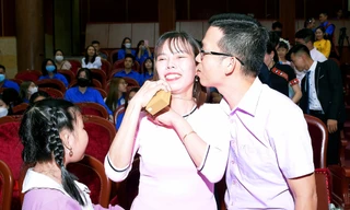 Anh Trần Mộng Hoàng (giáo viên ở Sóc Trăng) thể hiện cử chỉ yêu thương với vợ trong lễ tuyên dương "Gia đình trẻ Việt Nam tiêu biểu" năm 2022 Ảnh: Xuân Tùng 