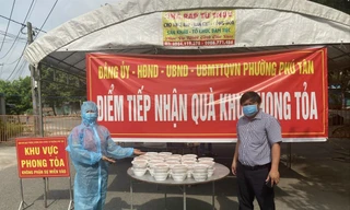 Chị Lê Thị Minh (bìa trái) mang suất ăn đến khu vực phong tỏa Ảnh: H.C 