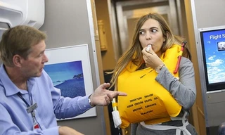 Nữ tiếp viên luyện tập cách hướng dẫn sử dụng áo phao trên máy bay. Ảnh minh họa: British Airways.