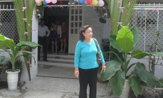 Bà Thủy trước cổng nhà kết hoa, trước khi đi đón con, sáng 24/4. ẢNH: HÒA HỘI